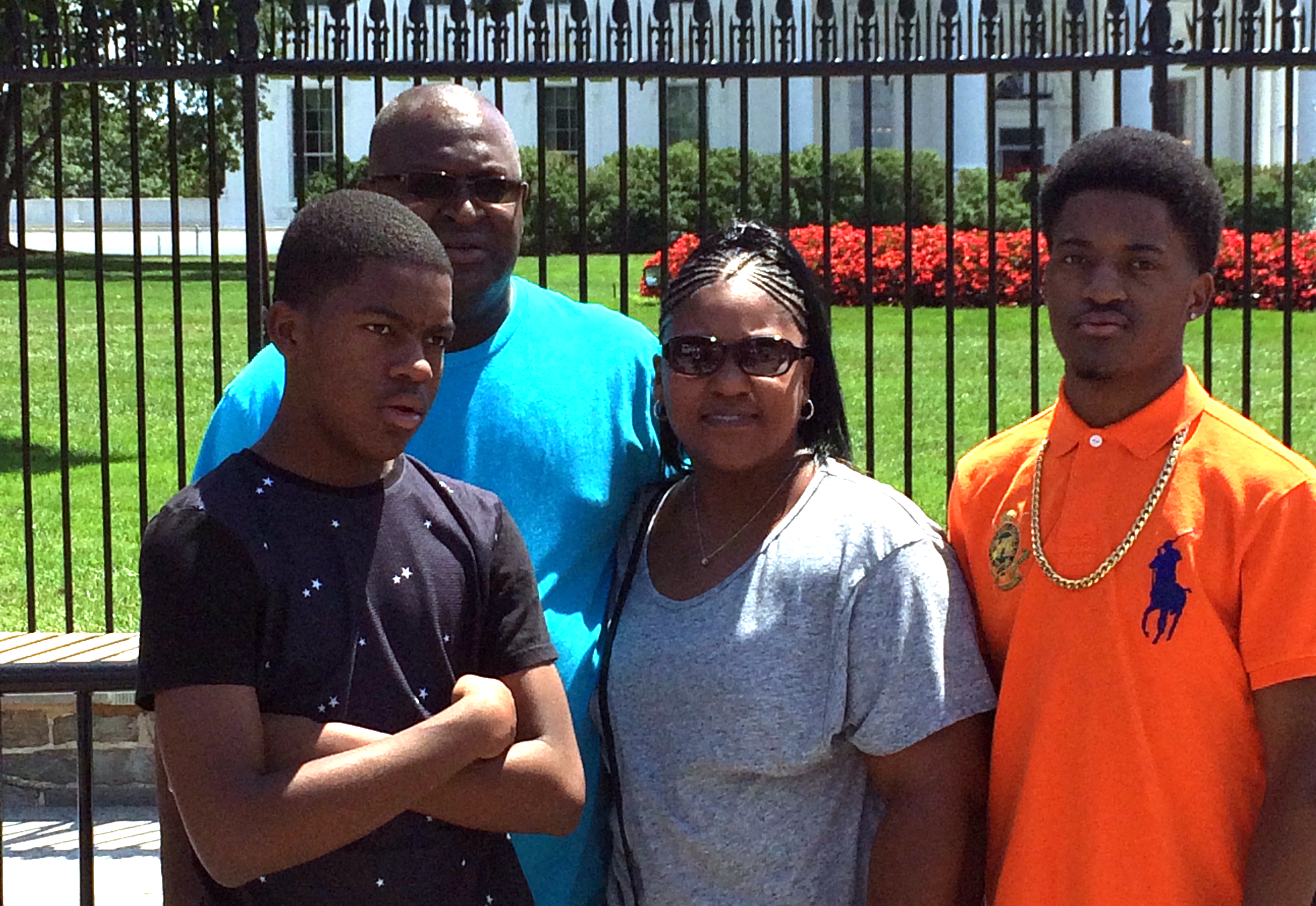 A Black family poses outside the White House gates, smiling for the camera