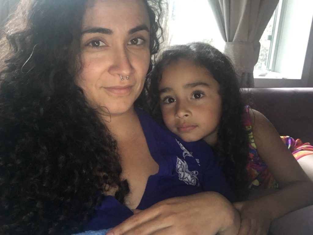 Curly haired woman with a septum nose ring takes a selfie with her daughter