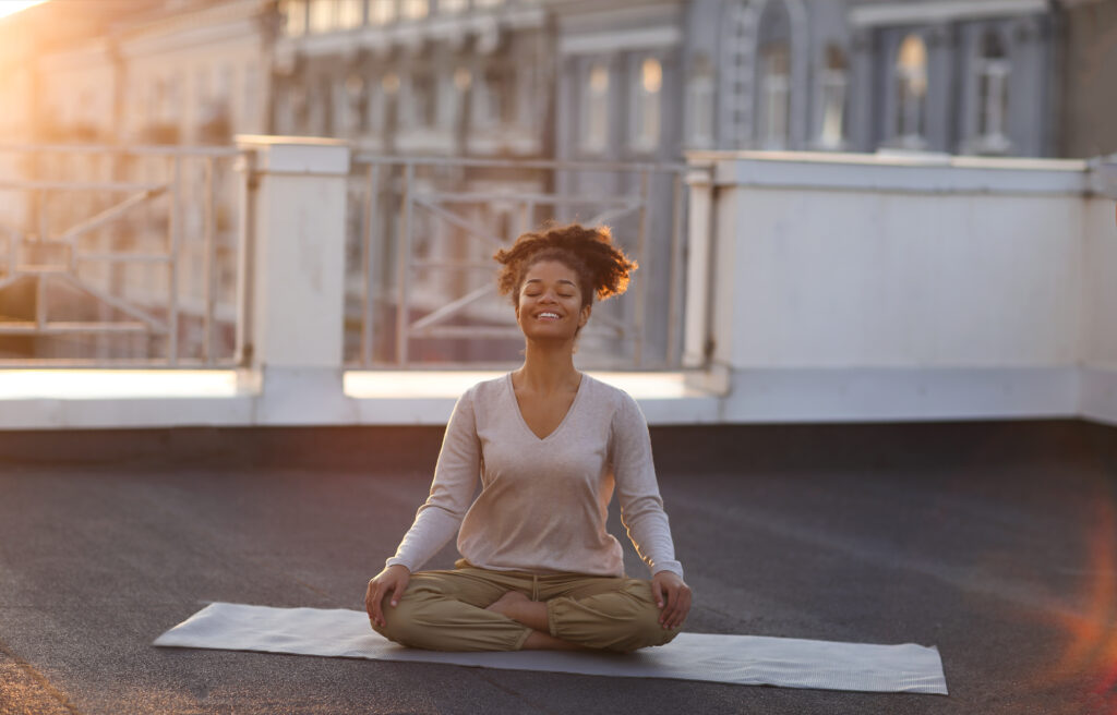 Cropped photo of  woman sitting in lotus pose on mat and practicing yoga, female doing namaste gesture while meditating indoors. Meditation and mindfulness concept