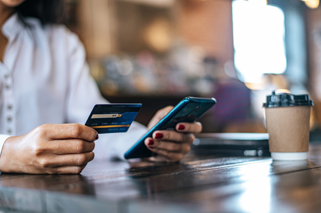 Pay for goods by credit card through a smartphone in a coffee shop.